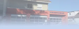 Feuerwache mit drei Garagentoren und Schriftzug 'FEUERWEHR' über dem rechten Tor