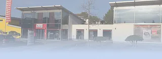 Eingang eines modernen Gewerbegebäudes mit Glasfassade und roten Bannern